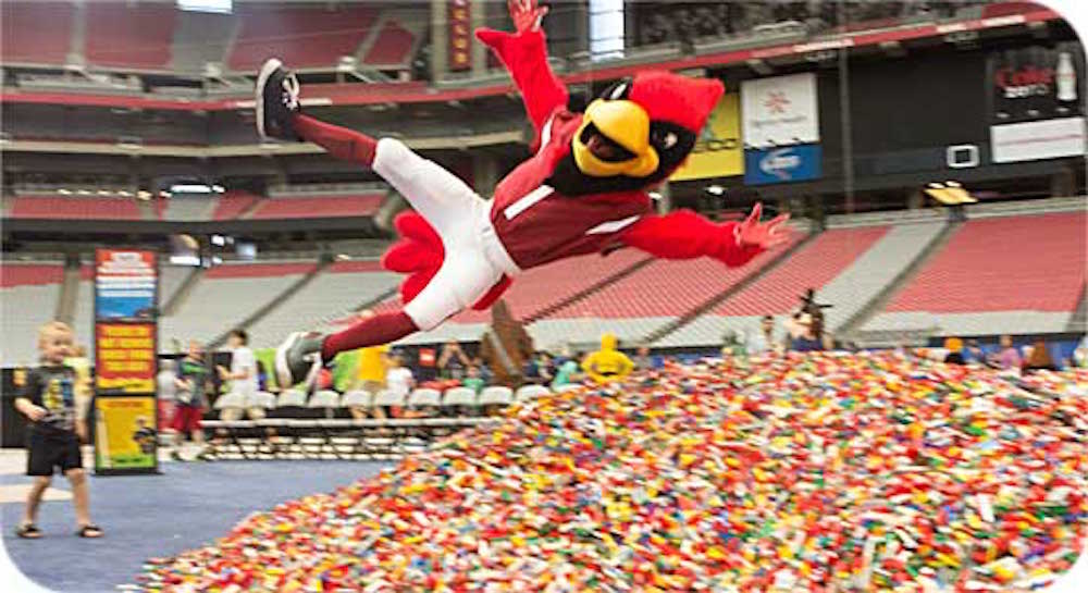 Arizona Cardinals mascot Big Red diving into a huge pile of LEGO bricks