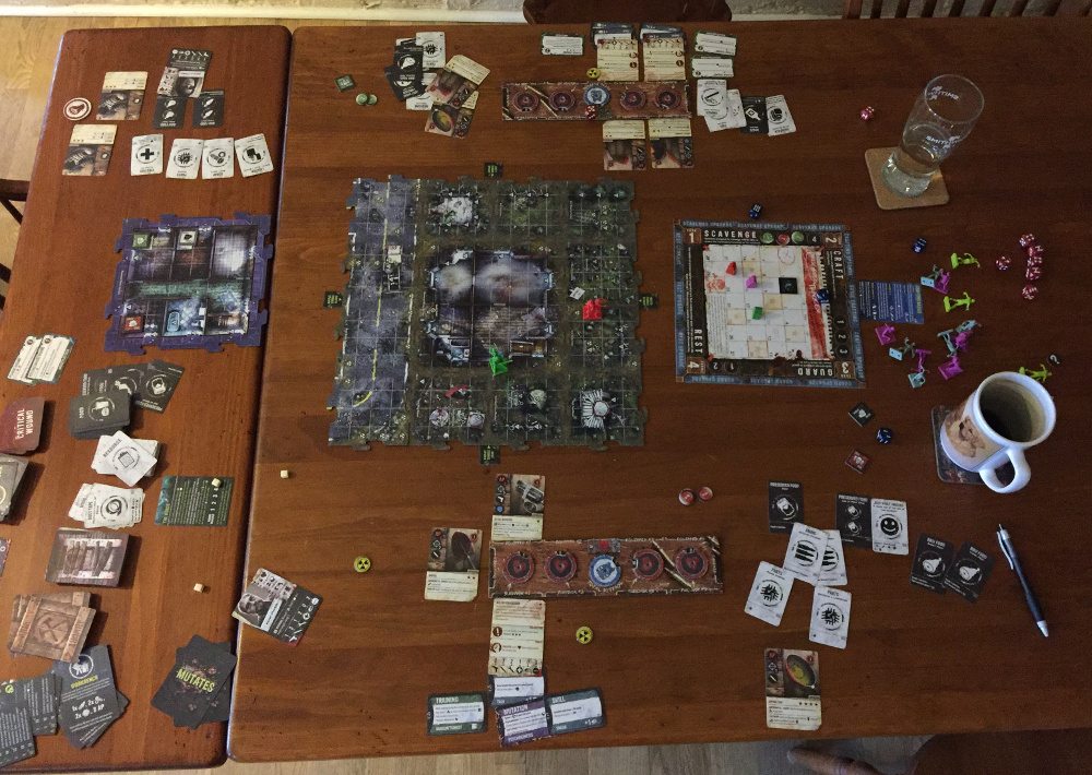 A large table (6' long at least) covered in a game of Zpocalypse 2.