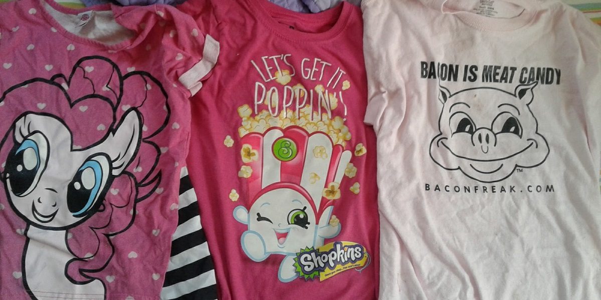Three t-shirts. One is the face of Pinky Pie. One is of the Shopkin "Poppy Corn." The last has a pig that says "Bacon Is Meat Candy" and the website baconfreak.com. All three shirts are pink.