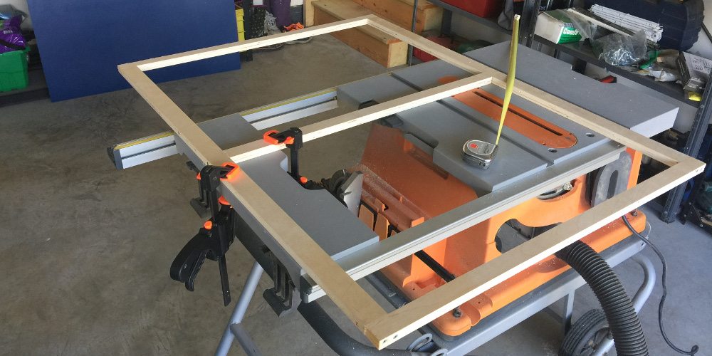 A wood frame clamped to a table saw.