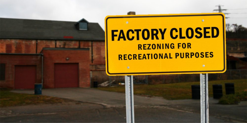 A sign in front of an old factory says Factory Closed, rezoning for recreational purposes